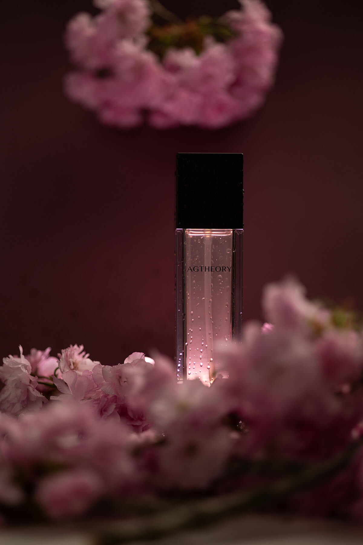 AXXZIA AGTheory Moisturizing Lotion на тлі справжніх гілок квітучої Сакури